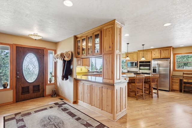 entryway with a wealth of natural light, a textured ceiling, and light hardwood / wood-style floors