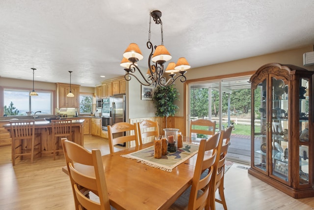 dining room featuring a notable chandelier, a textured ceiling, plenty of natural light, and light hardwood / wood-style floors