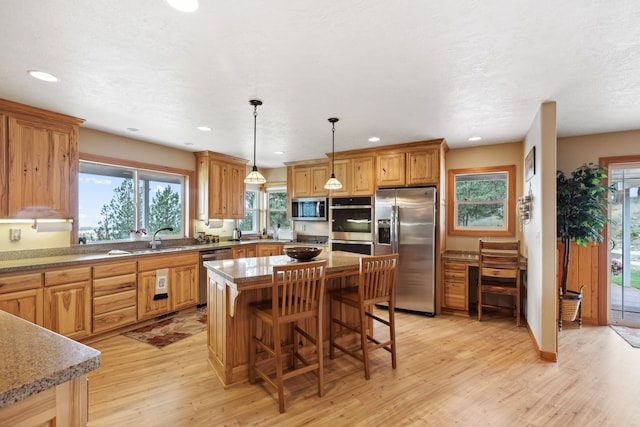 kitchen with stainless steel appliances, light hardwood / wood-style flooring, a center island, and a wealth of natural light