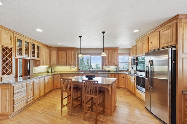 kitchen with light hardwood / wood-style flooring, a kitchen bar, stainless steel appliances, and a kitchen island