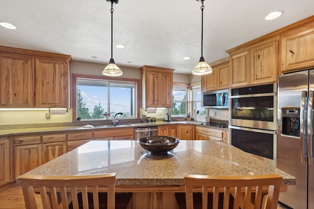 kitchen featuring a kitchen breakfast bar, sink, stainless steel appliances, and hanging light fixtures