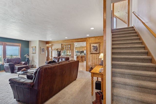 living room with a textured ceiling, wooden walls, and light carpet