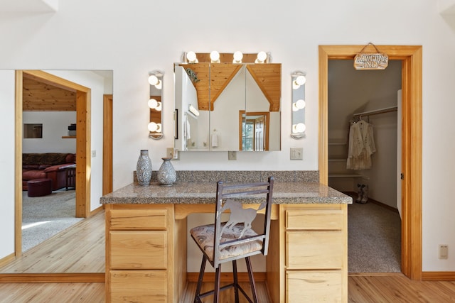 kitchen featuring kitchen peninsula, a breakfast bar area, light colored carpet, and light brown cabinetry