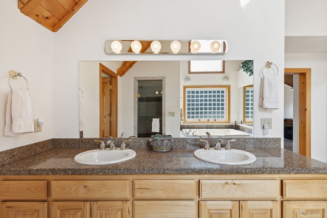 bathroom featuring dual vanity, a washtub, and lofted ceiling