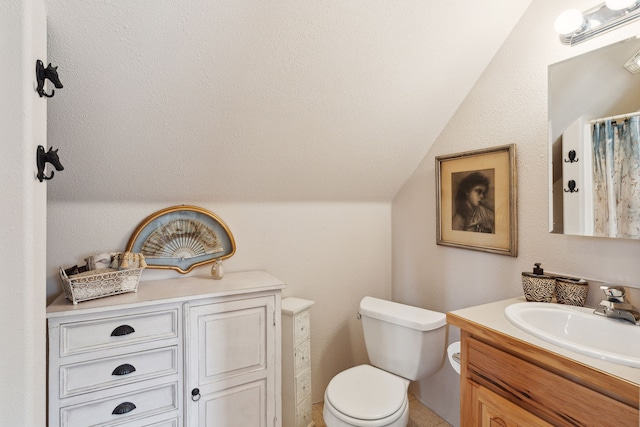 bathroom featuring toilet, vanity, and lofted ceiling