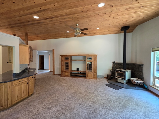 carpeted living room with high vaulted ceiling, ceiling fan, a wood stove, and wooden ceiling