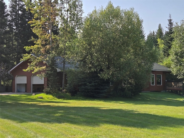 exterior space featuring a garage, a front lawn, and a wooden deck