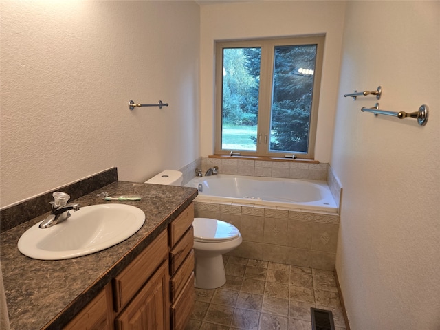 bathroom featuring tile patterned flooring, toilet, tiled tub, and vanity