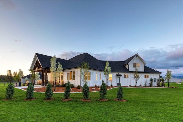 view of front of house with a lawn, board and batten siding, and a shingled roof