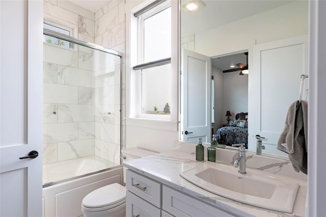 bathroom with shower / bath combination with glass door, vanity, ensuite bathroom, and toilet