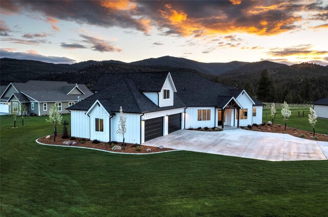 modern inspired farmhouse featuring a mountain view, a garage, and a lawn