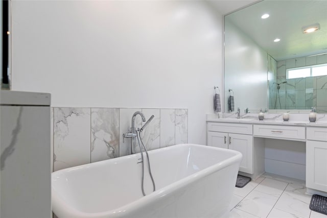 full bath with tile walls, recessed lighting, a soaking tub, marble finish floor, and vanity