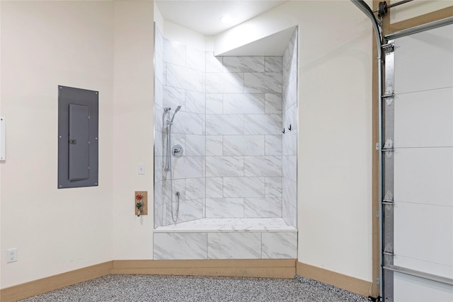 full bath featuring electric panel, a tile shower, and baseboards