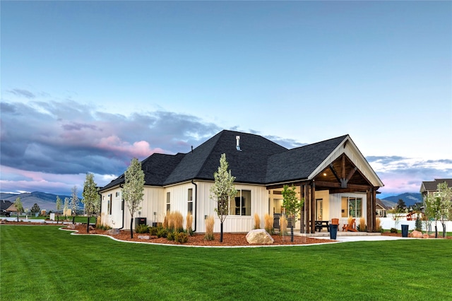 rear view of house with a yard, a mountain view, and a patio area