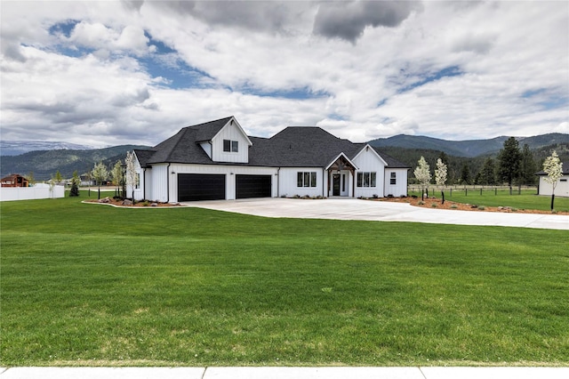 modern farmhouse style home with a mountain view, board and batten siding, a front yard, and fence