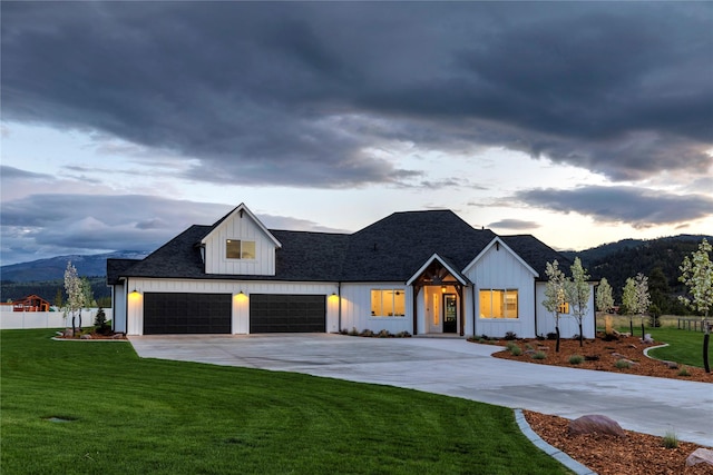 modern farmhouse featuring a front lawn, driveway, fence, a mountain view, and board and batten siding