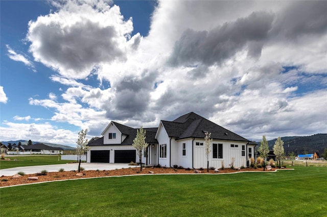 modern farmhouse style home featuring a front lawn, board and batten siding, driveway, and a shingled roof