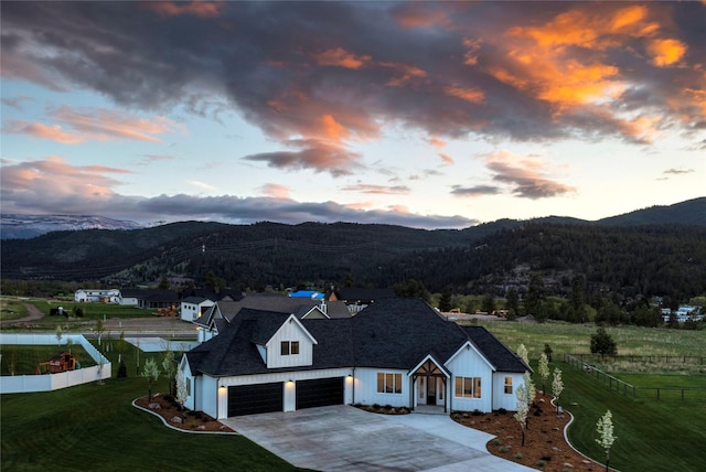 view of front of home featuring a mountain view, a yard, driveway, and fence