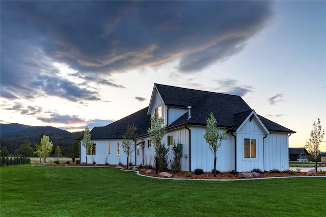 exterior space featuring a front yard, a mountain view, board and batten siding, and roof with shingles