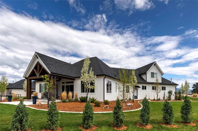 modern farmhouse style home featuring a front lawn, driveway, board and batten siding, and roof with shingles