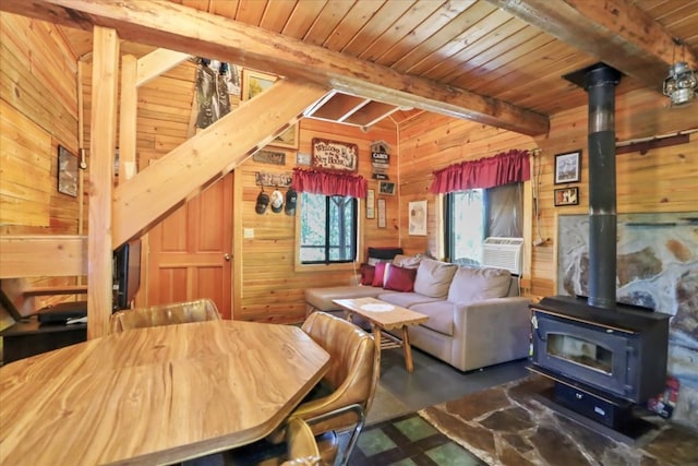 interior space featuring wood walls, wooden ceiling, a wood stove, cooling unit, and beamed ceiling