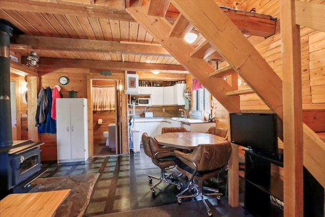 interior space with wood ceiling, beamed ceiling, wooden walls, and a wood stove