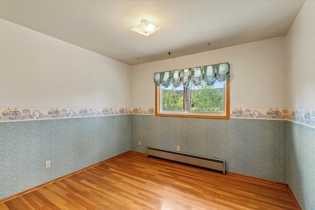 spare room with a baseboard radiator and hardwood / wood-style flooring