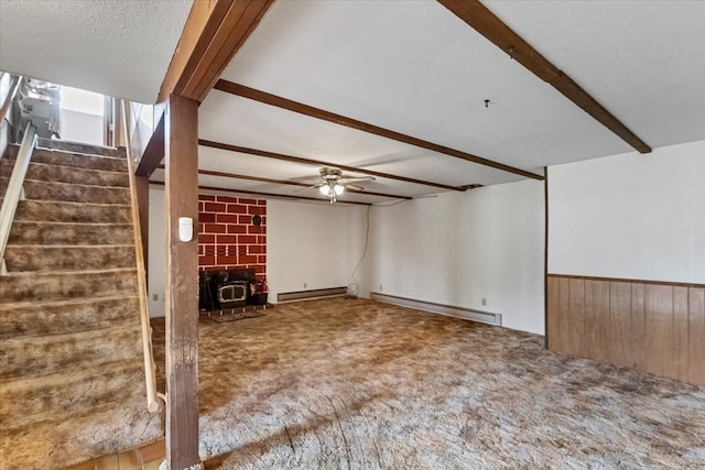 unfurnished living room featuring ceiling fan, brick wall, beamed ceiling, carpet flooring, and a wood stove