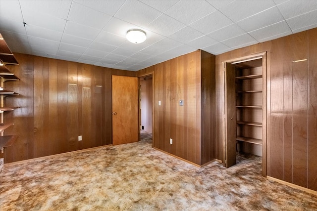 unfurnished room featuring wood walls and carpet floors