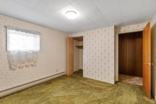 carpeted spare room with a baseboard heating unit