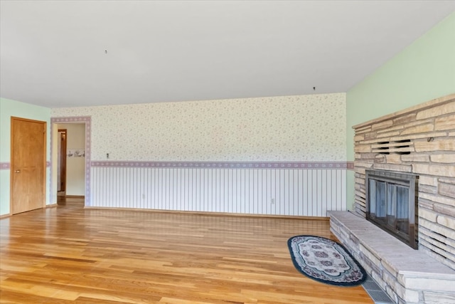 unfurnished living room with a stone fireplace and light hardwood / wood-style floors