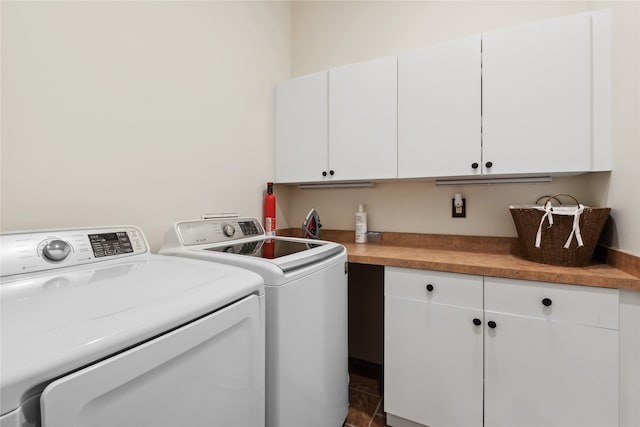 washroom with dark tile patterned flooring, independent washer and dryer, and cabinets