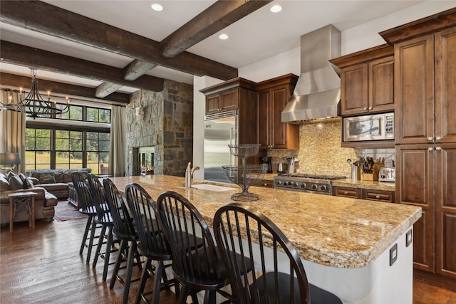 kitchen featuring built in appliances, light stone countertops, beamed ceiling, dark hardwood / wood-style floors, and wall chimney exhaust hood