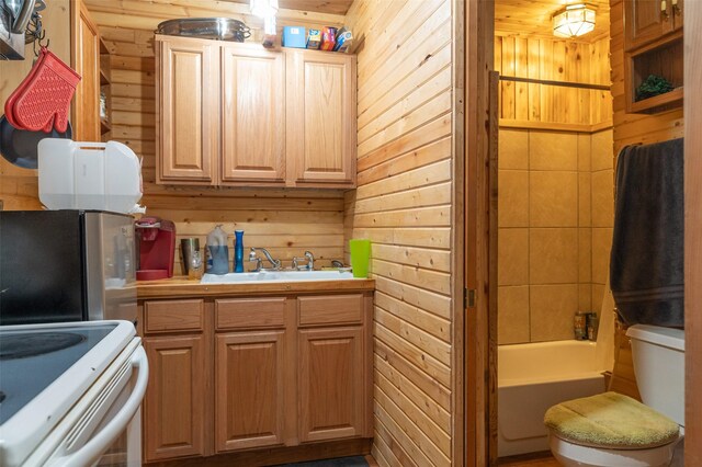 659 US Highway 2 E, Columbia Falls, MT 59912 - kitchen featuring white range with electric stovetop, light countertops, freestanding refrigerator, a sink, and wooden walls