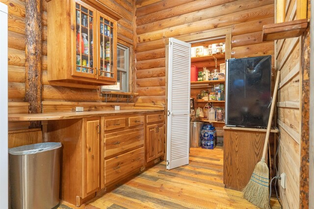 659 US Highway 2 E, Columbia Falls, MT 59912 - interior space with log walls, brown cabinetry, glass insert cabinets, and light wood-style floors
