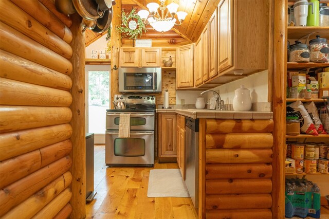 659 US Highway 2 E, Columbia Falls, MT 59912 - kitchen featuring light wood finished floors, tile counters, lofted ceiling, stainless steel appliances, and a chandelier
