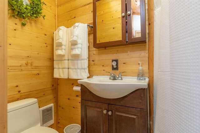 659 US Highway 2 E, Columbia Falls, MT 59912 - bathroom with toilet, wood walls, vanity, and visible vents