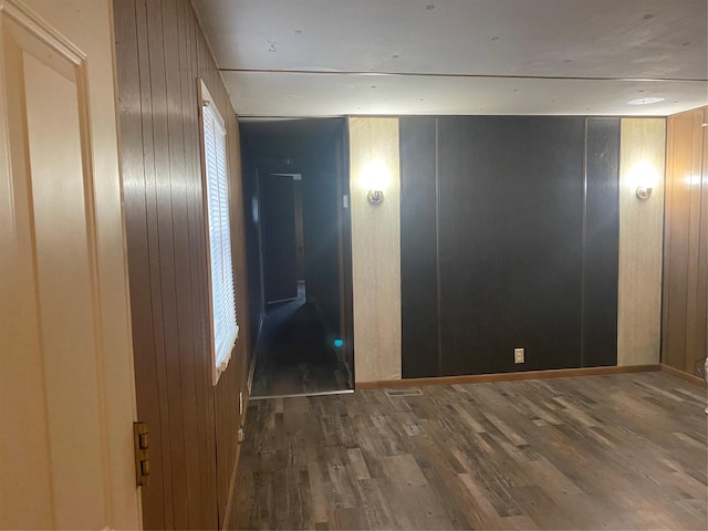 unfurnished bedroom with wood-type flooring and wood walls