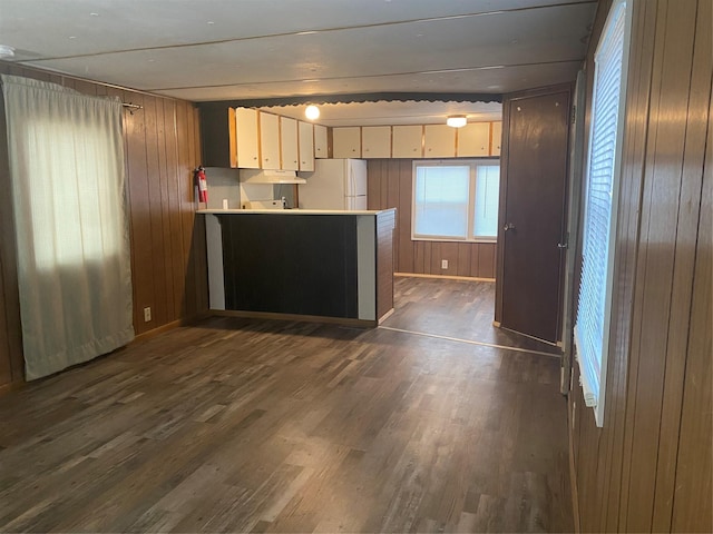 kitchen with white refrigerator, wooden walls, dark hardwood / wood-style flooring, and kitchen peninsula