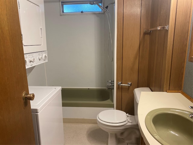 bathroom featuring stacked washer and clothes dryer, toilet, and sink