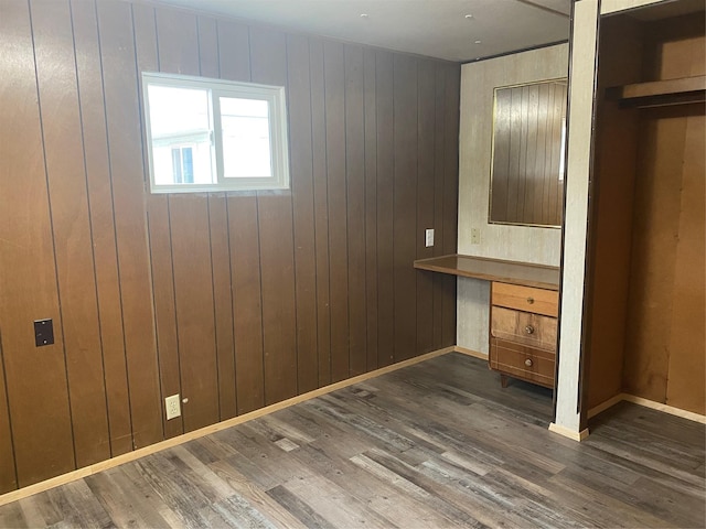 unfurnished bedroom with dark wood-type flooring and wood walls