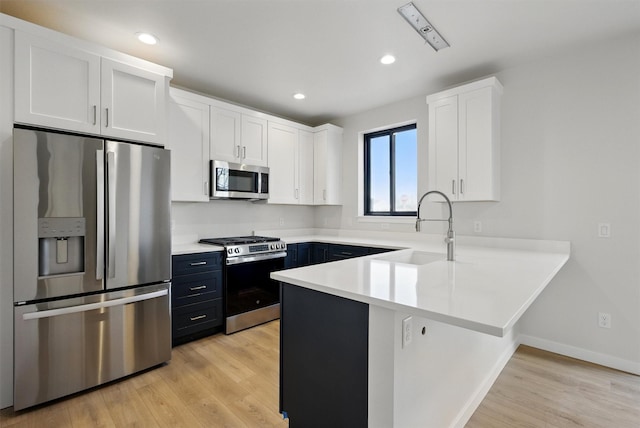 940 Kemp St Unit A, Missoula, MT 59801 - kitchen with appliances with stainless steel finishes, a peninsula, white cabinetry, light wood finished floors, and light countertops