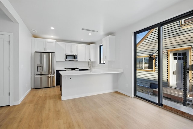 940 Kemp St Unit A, Missoula, MT 59801 - kitchen featuring stainless steel appliances, white cabinetry, light wood-style flooring, a peninsula, and light countertops