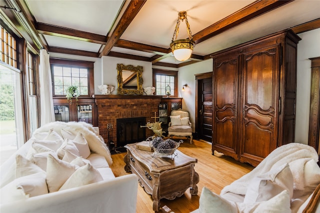 living room featuring a brick fireplace, beamed ceiling, light hardwood / wood-style flooring, and coffered ceiling