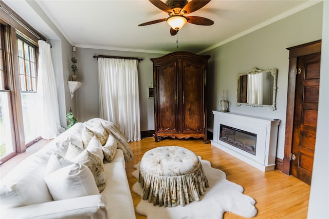 living room with ornamental molding, ceiling fan, and light hardwood / wood-style flooring