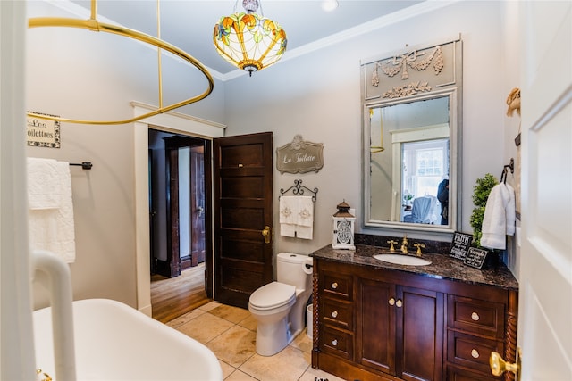 bathroom with tile patterned flooring, a tub, ornamental molding, vanity, and toilet