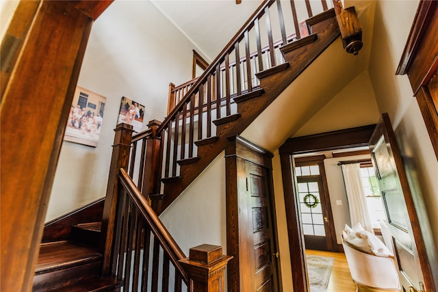 staircase with wood-type flooring and a towering ceiling