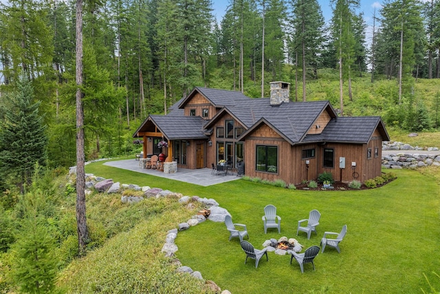 217 Pinto Trl, Bigfork, MT 59911 - rear view of property with a fire pit, a chimney, a patio, a yard, and a wooded view