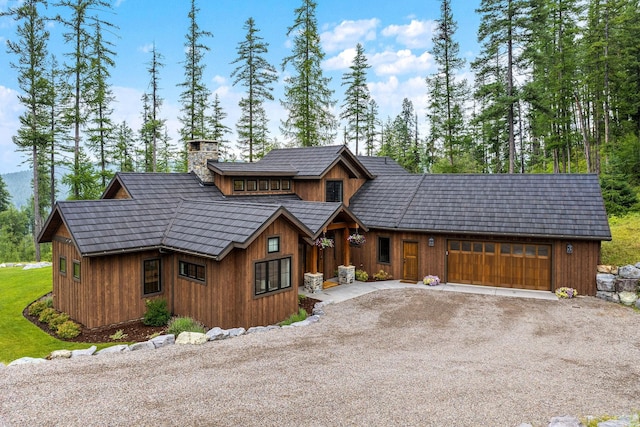 217 Pinto Trl, Bigfork, MT 59911 - chalet / cabin featuring driveway, an attached garage, and a chimney
