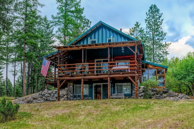 back of property featuring a wooden deck and a lawn